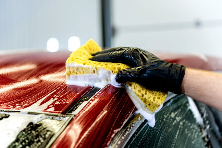 Worker washing red car with sponge on a car wash