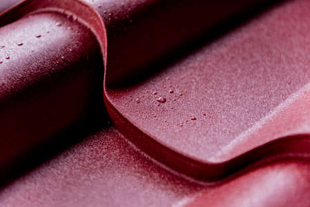 Red metallic roof tiles background with drops of water.の写真素材