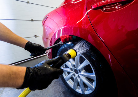 Cleaning the car wheel with a brush and water