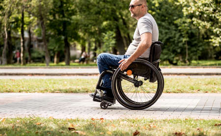 Handicapped man in wheelchair walk at the park alleyの写真素材