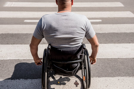 Handicapped man in wheelchair crossing street roadの写真素材