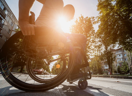 Handicapped man in wheelchair crossing street roadの写真素材