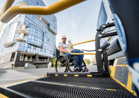 A man in a wheelchair moves to the lift of a specialized vehicleの写真素材