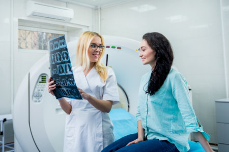 Radiologist with a female patient examining a CT scanの写真素材