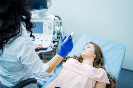 Doctor using ultrasound scanning machine for examining a thyroid of woman