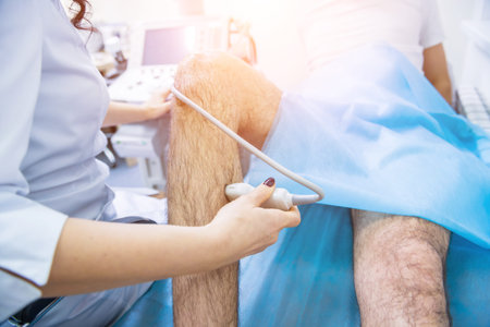 Doctor using ultrasound scanning machine examining injured knee