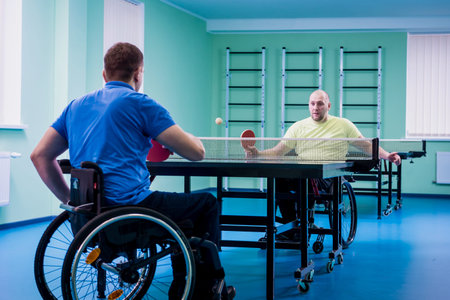 Adult disabled men in a wheelchair playing table tennis