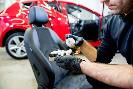 Car service worker cleans a car seat with a special brushの写真素材