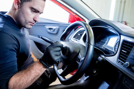 A car service worker cleans the car console with a special brushの写真素材