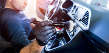 A car service worker cleans the car console with a special brushの写真素材