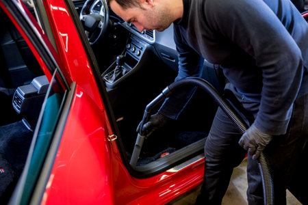 Car service worker cleaning car interior with a vacuum cleanerの写真素材