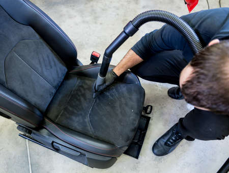 Car service worker cleaning car seat with vacuum cleaner.の写真素材