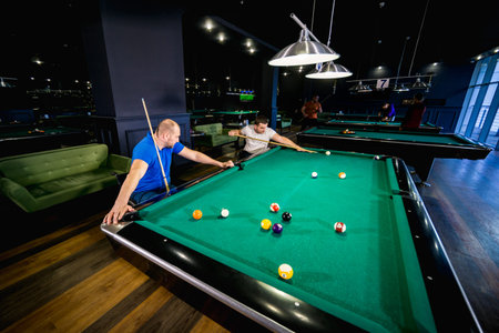 Adult men with disabilities in a wheelchair play billiards in the club