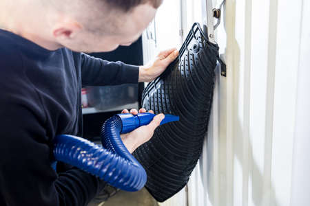 Man drying car carpet with vacuum cleaner after washingの写真素材