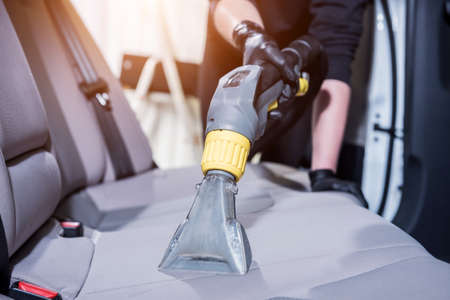 Worker cleans car interior with vacuum cleanerの写真素材