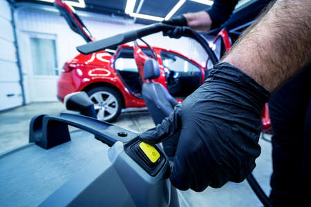 Car service worker cleaning car seat with vacuum cleaner.の写真素材