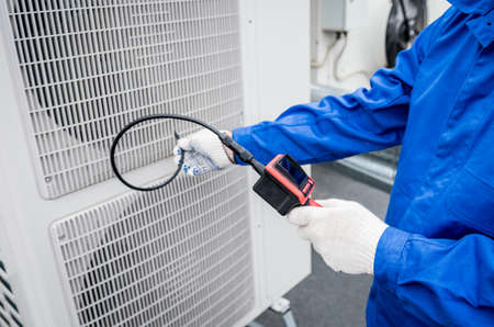 the technician uses a digital camera to check the clogging of the heat exchangerの写真素材