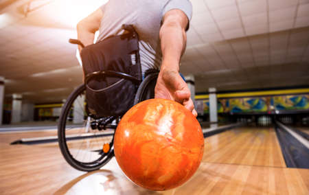 Young disabled man in wheelchair playing bowling in the clubの写真素材