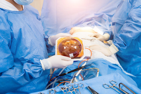 Surgeon in operation room is holding sterile breast silicone implant in hands.