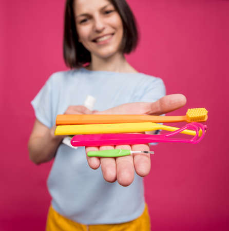 Beautiful young woman uses an oral care kit consisting of a tongue scraper, single tufted and interdental brushの写真素材
