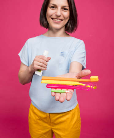 Beautiful young woman uses an oral care kit consisting of a tongue scraper, single tufted and interdental brushの写真素材