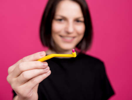 Beautiful happy young woman with single tufted toothbrush on blank pink backgroundの写真素材