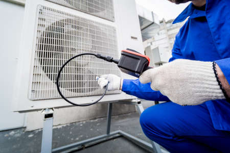 the technician uses a digital camera to check the clogging of the heat exchangerの写真素材