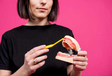 Beautiful happy young woman with single tufted toothbrush on blank pink backgroundの写真素材