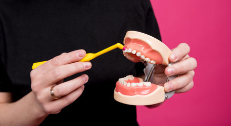 Beautiful happy young woman with single tufted toothbrush on blank pink background
