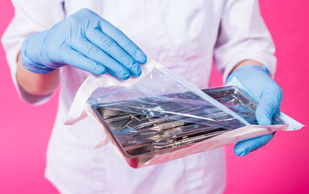 Woman dentist opens a package of sterile dental instrumentsの写真素材