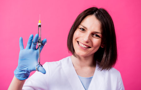 Woman dentist with a carpool syringe injects anesthetic into the gum of the artificial skullの写真素材