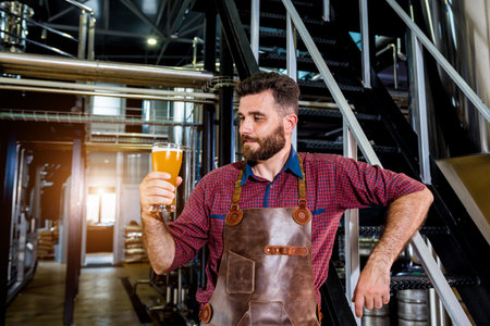 Young male brewer in leather apron at modern brewery factory