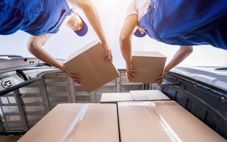 Two removal company workers unloading boxes from minibus