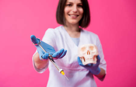 Woman dentist with a carpool syringe injects anesthetic into the gum of the artificial skullの写真素材