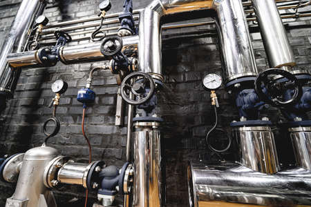 The valves and pipes at a craft modern brewery wallの写真素材