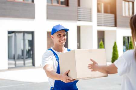 Young courier delivering goods to a young woman at homeの写真素材