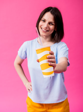 Young woman with sensitive teeth drinking cold water on color backgroundの写真素材