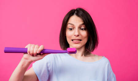 Beautiful happy young woman with big toothbrush on blank pink backgroundの写真素材