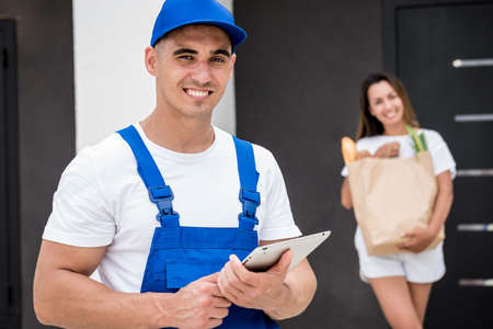 Young courier delivering goods to a young woman at homeの写真素材