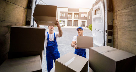 Two removal company workers unloading boxes from minibus