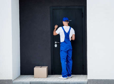 Young courier delivers goods to the door of the houseの写真素材