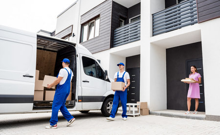 Two removal company workers are loading boxes into a minibus.