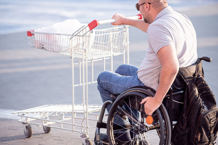 Person with a physical disability pushing cart in front of himself at supermarket parking