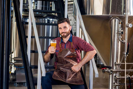 Young male brewer in leather apron at modern brewery factoryの写真素材