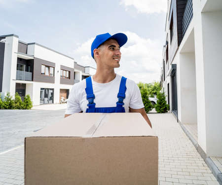 Young delivery man hold a cardboard box in his handsの写真素材