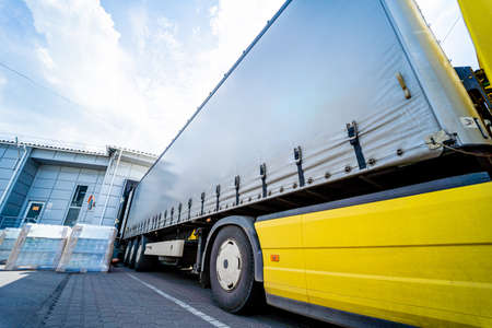 Large trucks near warehouse against blue sky backgroundの写真素材