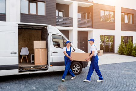Two removal company workers are loading boxes into a minibus.の写真素材