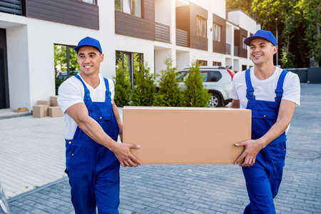 Two removal company workers are loading boxes into a minibus.の写真素材