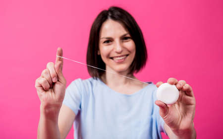 Beautiful young woman use dental floss on pink backgroundの写真素材