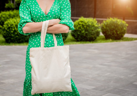 Young beautiful woman with linen eco bag on city background.